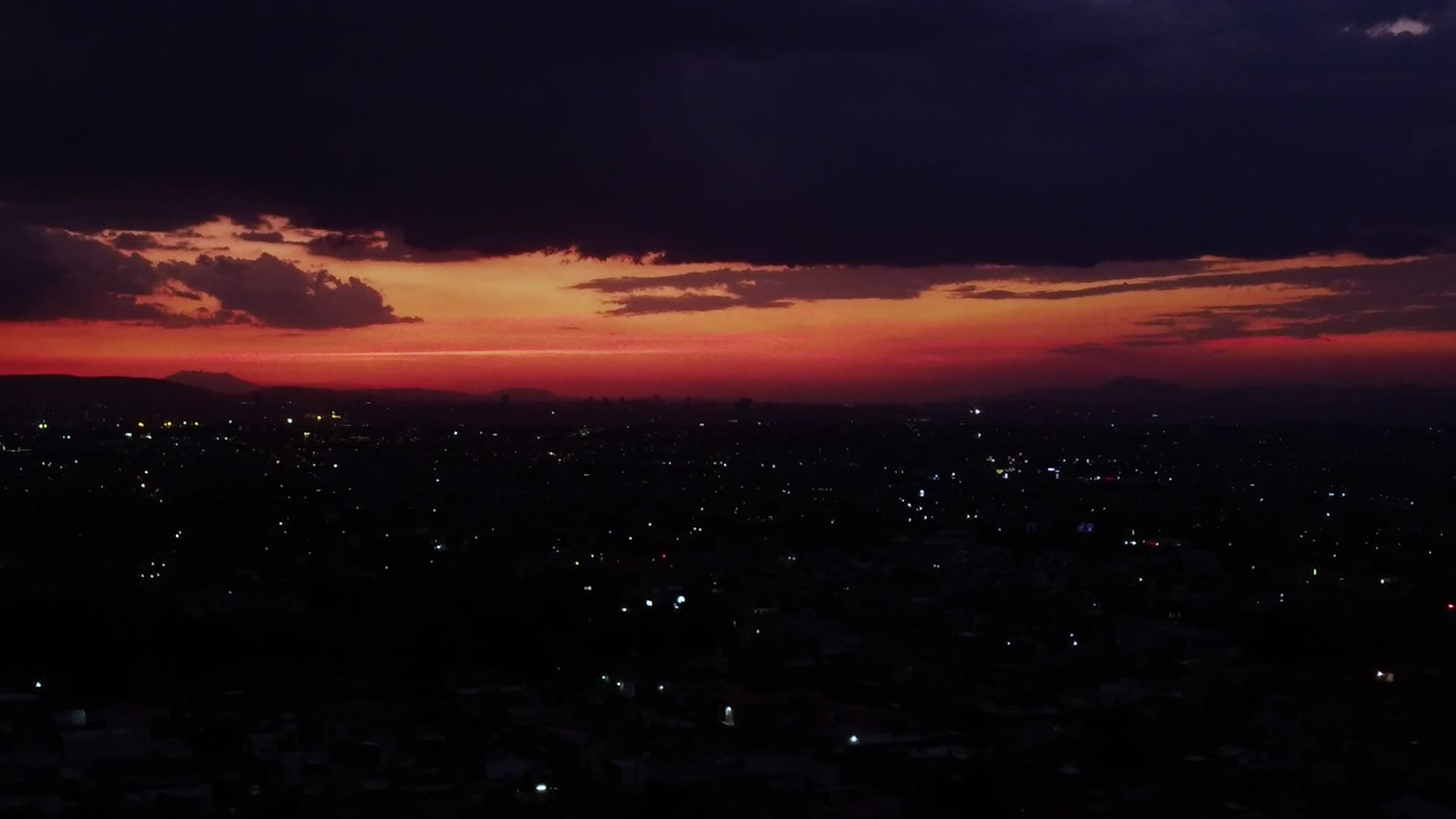 Red and orange sunset clouds over a dark city