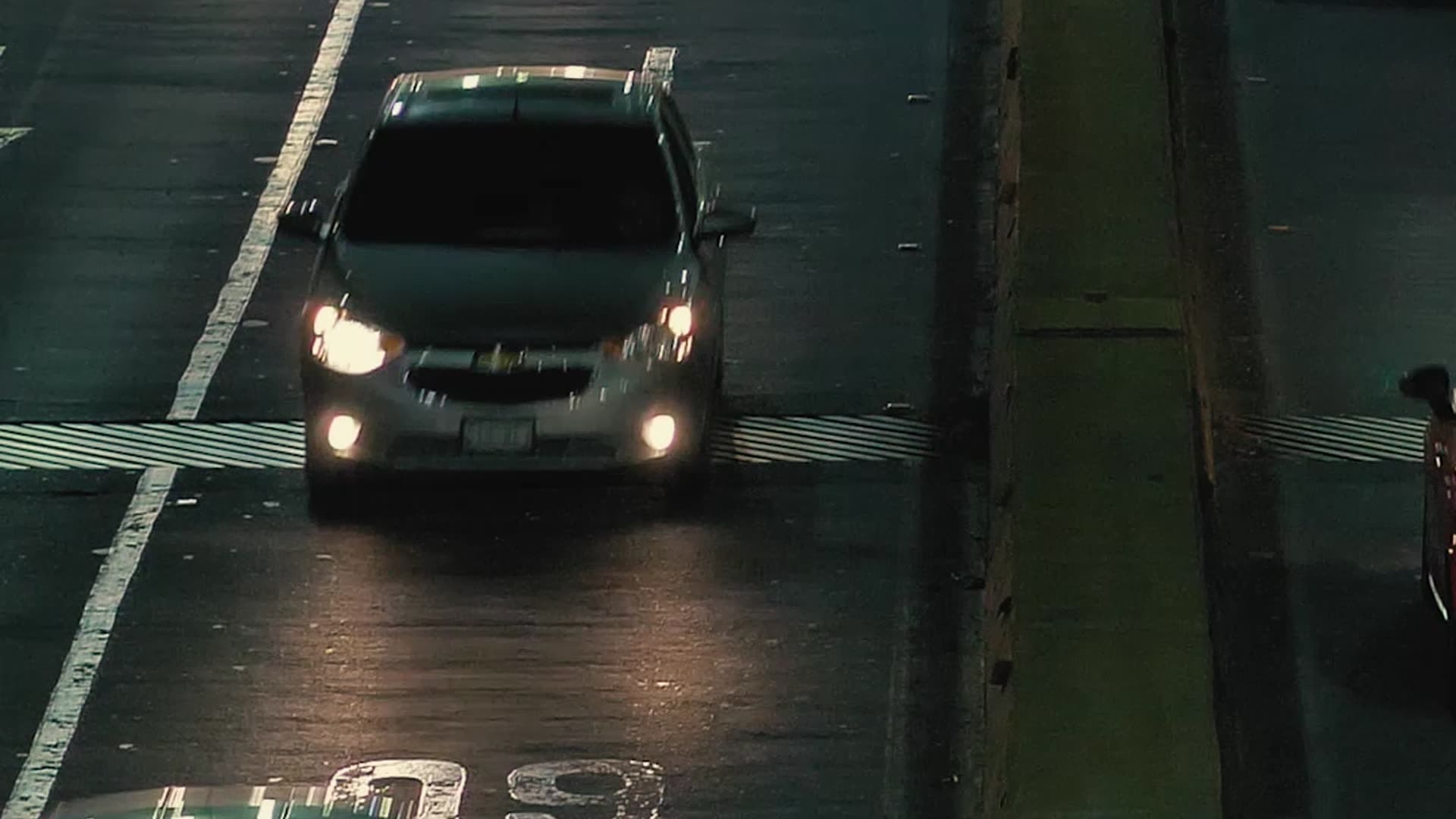 Car headlights on a wet city road at night